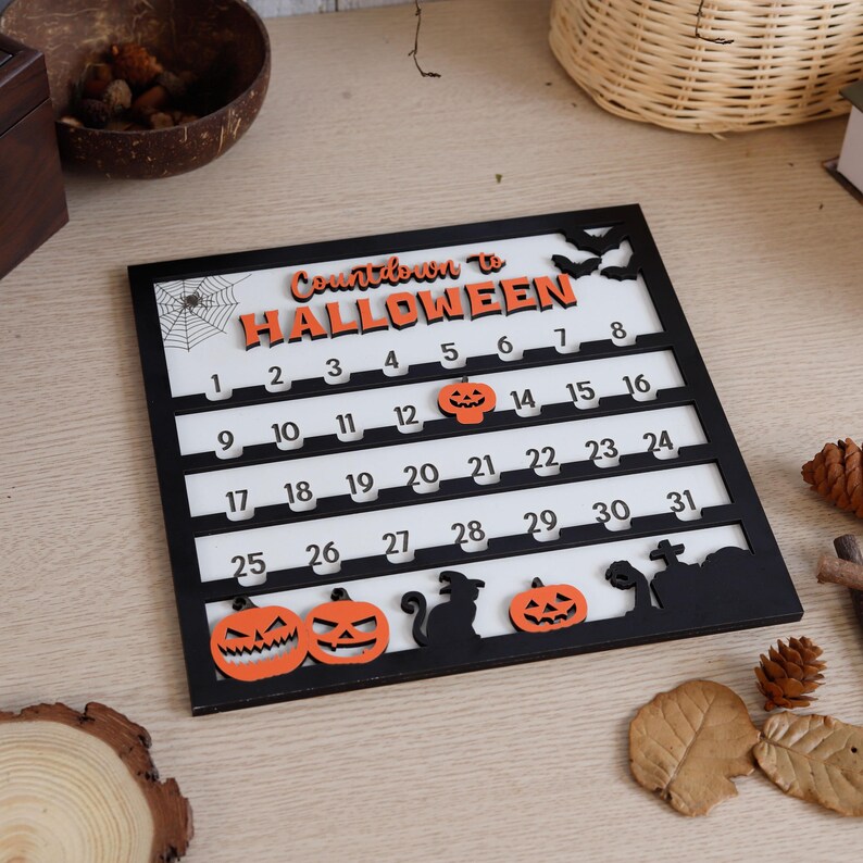 May include: A black and white Halloween countdown calendar with orange accents. The calendar features the text "Countdown to Halloween" and numbered days. Decorative pumpkins, bats, and a cat silhouette are included.