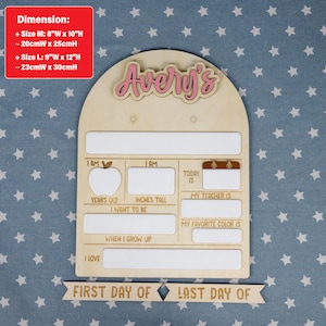 May include: Wooden school board with the name "Avery's" in pink. The board has spaces for "Years Old," "Inches Tall," "My Teacher Is," and "My Favorite Color Is." Includes a banner that reads "First Day Of" and "Last Day Of."