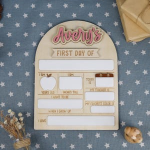 May include: Wooden first day of school sign with the name "Avery's" in pink. The sign has spaces to fill in information about the child's first day, including age, height, teacher, and favorite color.