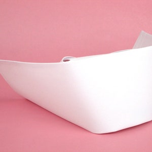 May include: A white nurse's cap, folded in half, with a smooth, flat surface. The cap is made of a thin, flexible material.