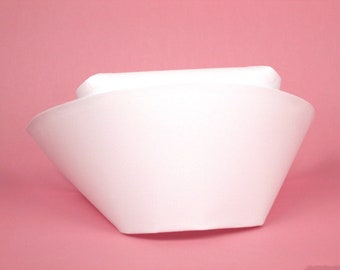 May include: A white nurse's cap with a wide brim and a flat top. The cap is made of a smooth, white fabric.