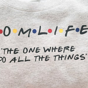 May include: Gray sweatshirt with the text "M.O.M.L.I.F.E." in black with colorful dots, and the text "The One Where I Do All The Things" in black.