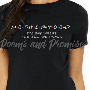 May include: Black t-shirt with the word "MOTHERHOOD" in colorful letters, styled like the TV show "Friends". Below, the text reads "THE ONE WHERE I DO ALL THE THINGS". The shirt also has the words "Poems and Promises" in script.