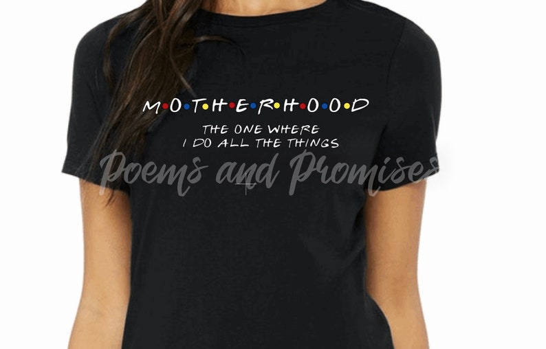 May include: Black t-shirt with the word "MOTHERHOOD" in colorful letters, styled like the TV show "Friends". Below, the text reads "THE ONE WHERE I DO ALL THE THINGS". The shirt also has the words "Poems and Promises" in script.
