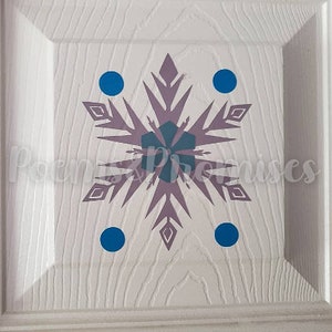 K&ouml;nnte beinhalten: Eine wei&szlig;e T&uuml;r mit einem violetten Schneeflocken-Design und vier blauen Kreisen darum herum.