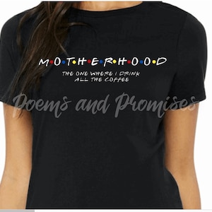 May include: Black t-shirt with the word "MOTHERHOOD" in a colorful, stylized font, with the text "THE ONE WHERE I DRINK ALL THE COFFEE" below. The shirt also has the text "Poems and Promises" in a cursive font.