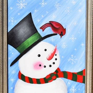 May include: A framed painting of a snowman with a black top hat and a red cardinal bird. The snowman has a red and green scarf, a carrot nose, and rosy cheeks. The background is light blue with white snowflakes.