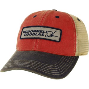 Peut inclure: Une casquette de baseball avec un panneau avant rouge et une visière gris foncé avec des coutures visibles. Les panneaux latéraux et arrière sont en maille beige. Un écusson rectangulaire affiche le texte McDonnell Douglas en noir.