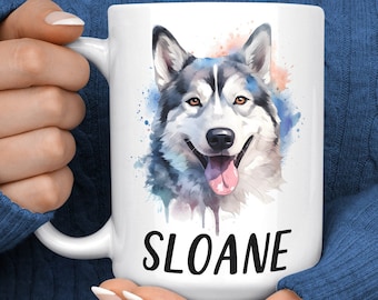 Può includere: Tazza in ceramica bianca con un'illustrazione ad acquerello di un cane Husky siberiano con occhi azzurri e lingua rosa. Il nome del cane, "SLOANE", è stampato in nero sotto l'immagine.