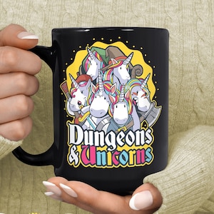 May include: Black ceramic mug with a white and colorful illustration of five unicorns wearing medieval garb and holding weapons. The text "Dungeons & Unicorns" is printed in white below the unicorns.