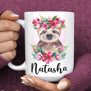 May include: White ceramic mug featuring a sloth wearing a pink flower crown. The mug has the name "Natasha" printed on the front.