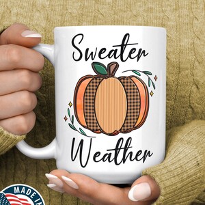 May include: White ceramic mug with a black and orange pumpkin design and the text "Sweater Weather".