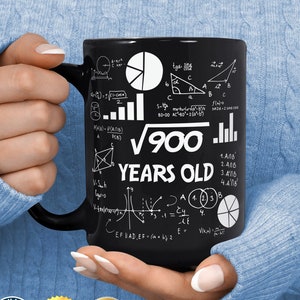 May include: Black coffee mug with a white design of mathematical equations and the text "√900 YEARS OLD".
