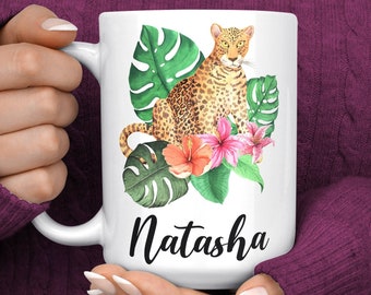 May include: White ceramic mug with a colorful illustration of a leopard sitting in a tropical jungle setting. The mug has the name "Natasha" printed on the front.