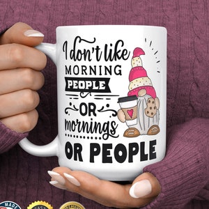 May include: White ceramic mug with the text "I don't like MORNING PEOPLE OR mornings OR PEOPLE." A cartoon gnome with a pink hat, holding a coffee cup and cookie is on the right side of the mug.