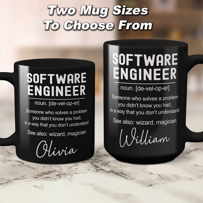 K&ouml;nnte beinhalten: Zwei schwarze Kaffeetassen mit wei&szlig;em Design. Die Tassen zeigen die Definition eines Softwareentwicklers mit den Worten "Software Engineer" und "noun. [de-vel-op-er]" oben. Die Tassen haben die Namen "Olivia" und "William" unten.