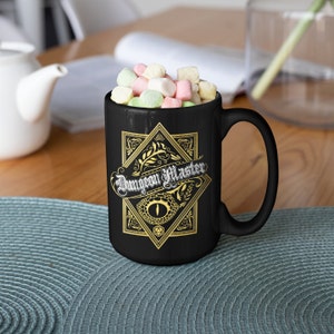 May include: Black ceramic mug with a gold design featuring a dragon's eye and the text "Dungeon Master".