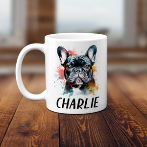 Pode incluir: Caneca de cer&acirc;mica branca com uma ilustra&ccedil;&atilde;o em aquarela de um bulldogue franc&ecirc;s. O c&atilde;o &eacute; preto com marcas brancas e tem um respingo de tinta colorida atr&aacute;s. O nome "CHARLIE" est&aacute; impresso em preto abaixo do c&atilde;o.