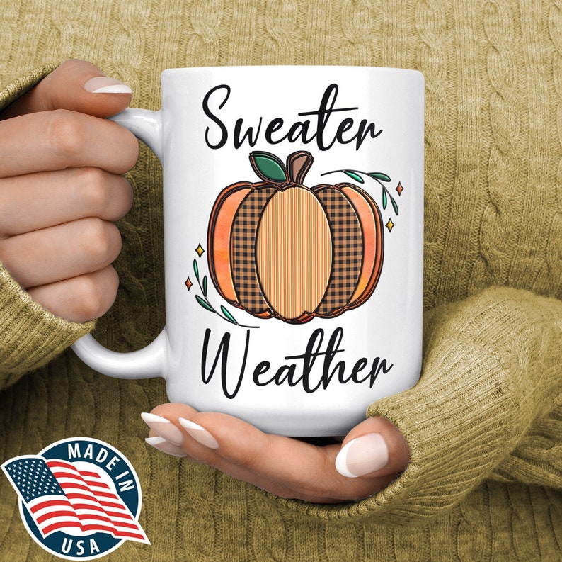 May include: White ceramic mug with a black and orange pumpkin design and the text "Sweater Weather".
