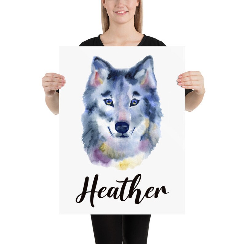 May include: A watercolor print featuring a wolf's head with blue, purple, and yellow hues. The name "Heather" is written in a cursive font below the wolf illustration. The artwork is displayed on a white background.