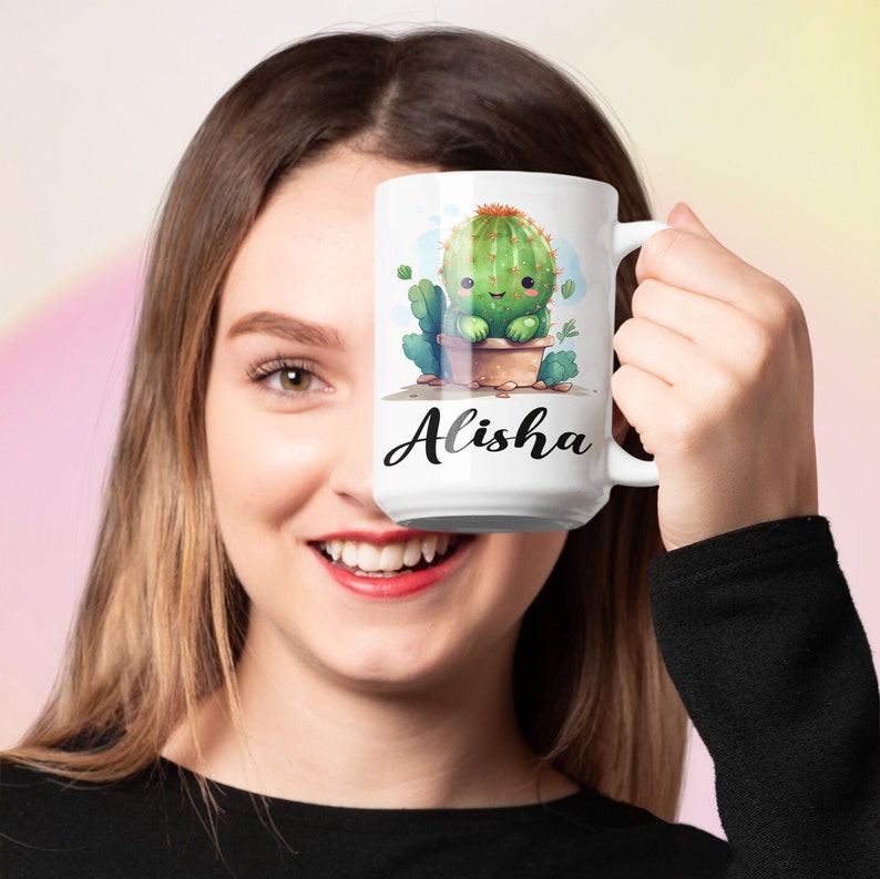 May include: White ceramic mug with a cartoon cactus illustration and the name "Alisha" printed on the front.
