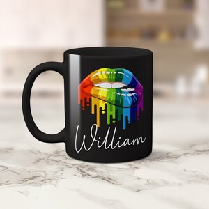 May include: Black coffee mug with a rainbow dripping lips design and the name "William" printed in white.