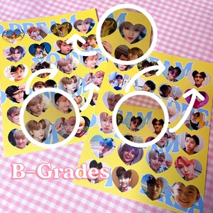 Op de afbeelding: Twee gele en blauwe kaarten met hartvormige stickers met verschillende foto's van een K-pop boyband. De kaarten zijn gelabeld met "Dream" en "B-Grades".