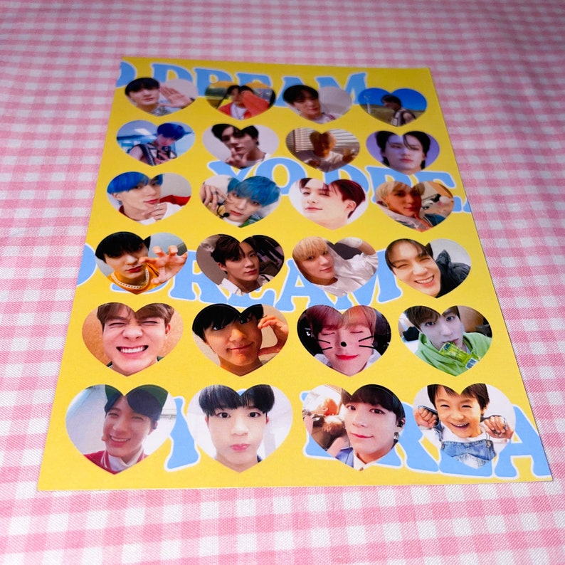 Op de afbeelding: Een gele kaart met blauwe harten met foto's van een K-pop boyband. De tekst "Dream You" is in blauw op de kaart gedrukt.