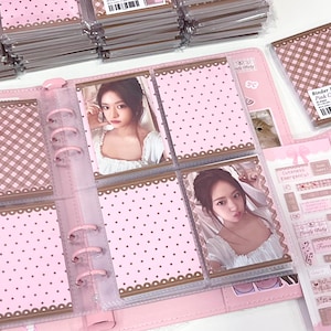 Könnte beinhalten: Rosa Fotoalbum mit Ringbuchbindung, mit Bildern einer Person. Das Album hat ein Tupfenmuster mit braunem Rand und ist von anderen Alben und Aufklebern umgeben. Der Text "Lovely Baby" ist sichtbar.