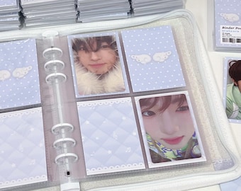 May include: A clear, zippered binder with multiple pages filled with photo cards. The cards are in clear plastic sleeves and feature images of a person. The binder pages have a light blue background with a quilted pattern and decorative elements.