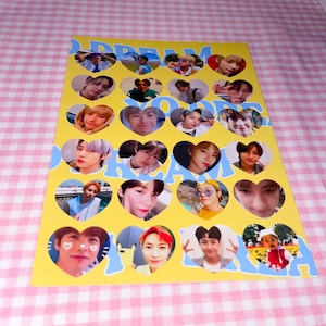 Op de afbeelding: Een gele en blauwe stickervel met hartvormige frames met foto's van een jongensband. De tekst "DREAM YOU'RE DREAM" staat op het vel gedrukt.