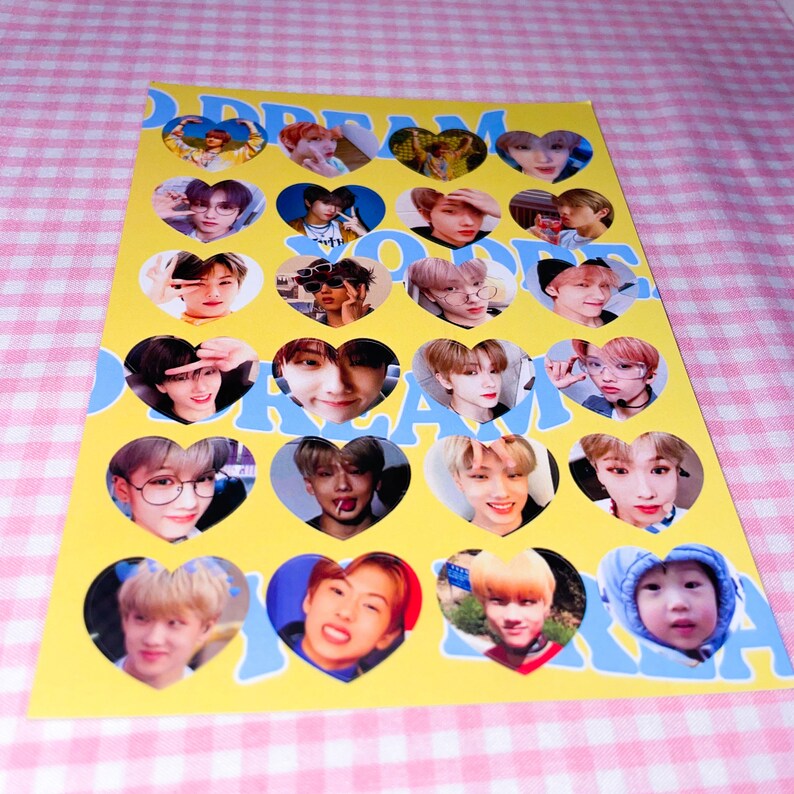 Op de afbeelding: Een gele en blauwe poster met de woorden "DREAM" en "KOREA" in grote letters. Er zijn 18 hartvormige afbeeldingen van verschillende leden van de K-pop groep NCT Dream.