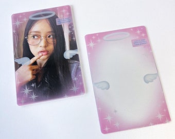 May include: Two pink photo cards with a white halo and wings design. One card features a photo of a young woman with glasses and a halo. The text on the card reads "Did it make you feel better?" The other card is blank.