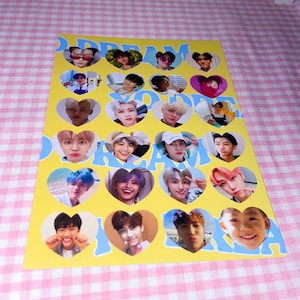 Op de afbeelding: Een gele kaart met blauwe harten met foto's van een K-pop boyband. De tekst "DREAM" en "YOU" staat in blauwe letters op de kaart.