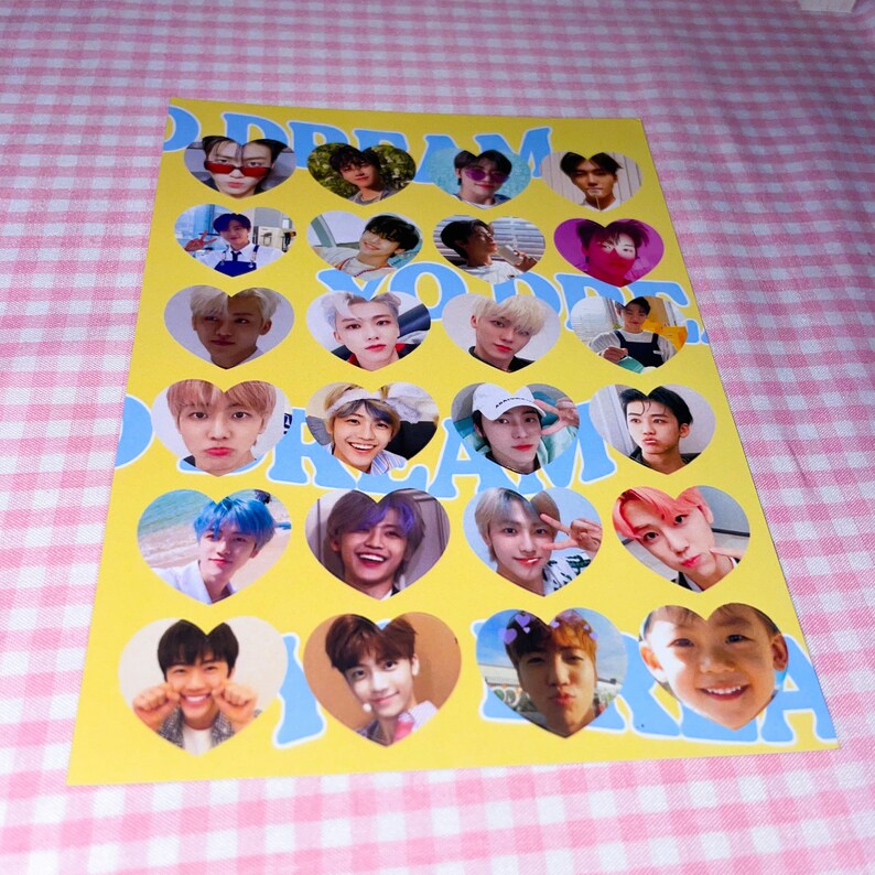 Op de afbeelding: Een gele kaart met blauwe harten met foto's van een K-pop boyband. De tekst "DREAM" en "YOU" staat in blauwe letters op de kaart.