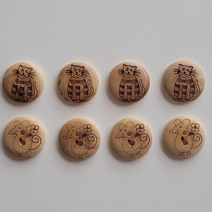 Könnte beinhalten: Acht Holz-Knöpfe mit natürlicher Holzoptik. Vier Knöpfe zeigen ein Katzenmotiv und vier Knöpfe zeigen ein Mausmotiv.