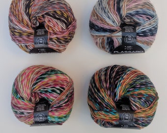 May include: Four balls of multi-coloured yarn, each with a label. The yarn is a mix of colours including pink, black, yellow, and blue. The yarn is tightly wound and appears soft.