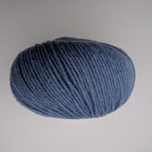 May include: A ball of blue yarn, tightly wound, with visible strands. The yarn has a soft, matte appearance and is suitable for knitting or crocheting projects. The color is a muted, dusty blue.