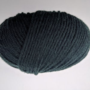 May include: A ball of dark teal yarn, tightly wound and textured. The yarn appears soft and is suitable for knitting or crocheting projects. The color is a deep, muted shade of green-blue.