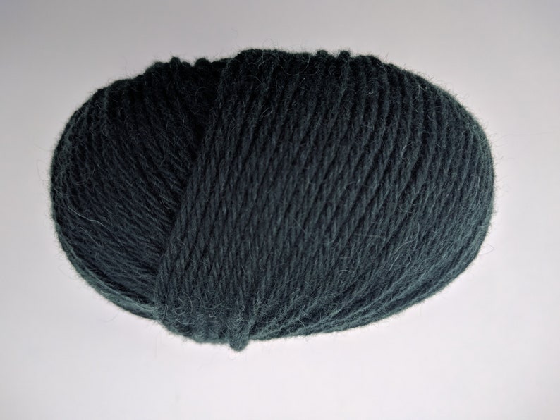 May include: A ball of dark teal yarn, tightly wound and textured. The yarn appears soft and is suitable for knitting or crocheting projects. The color is a deep, muted shade of green-blue.