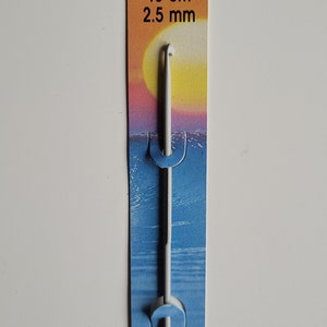May include: A white Pony brand crochet hook with a 2.5 mm size, packaged on a yellow, orange, and blue card with the text "Pony 15 cm 2.5 mm # 45603 MADE IN INDIA".