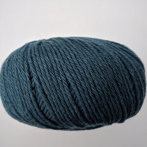 May include: A ball of teal-colored yarn, tightly wound and oval-shaped. The yarn appears to be made of a soft, textured material, ideal for knitting or crocheting projects. The yarn is a solid color with no visible patterns.
