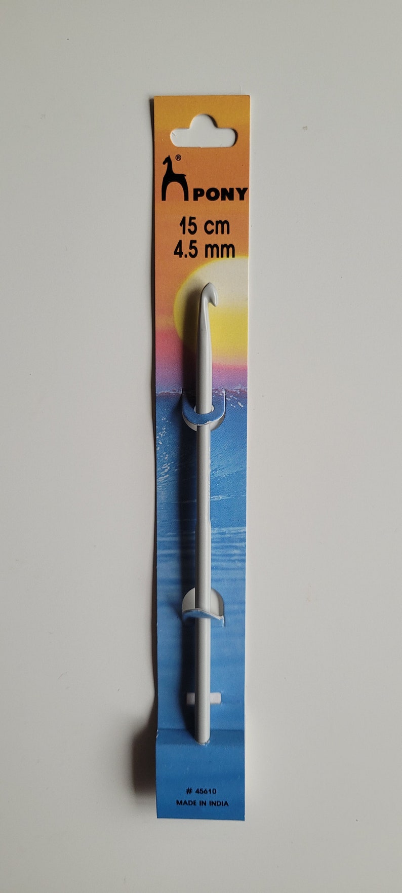 May include: White plastic crochet hook with a 4.5 mm size, packaged on a blue and yellow card with the brand name "PONY" and the text "15 cm" and "# 45610 MADE IN INDIA".