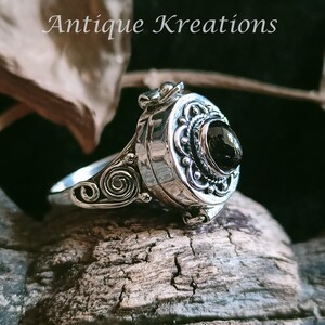 K&ouml;nnte beinhalten: Ein silberner Ring mit einem schwarzen Stein und filigranen Details. Der Ring ist ein Medaillon, das sich &ouml;ffnet und ein kleines Fach enth&uuml;llt.