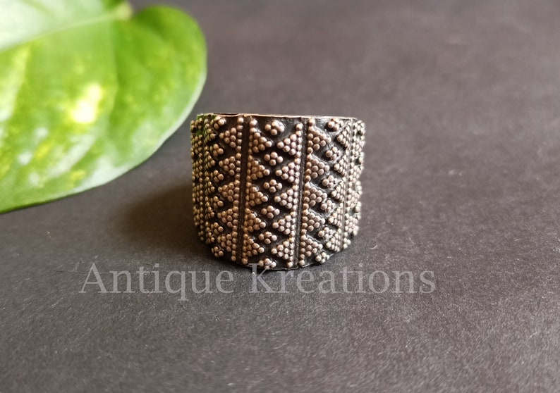 K&ouml;nnte beinhalten: Ein silberner Ring mit einem geometrischen Muster aus kleinen Punkten, die Dreiecke bilden. Der Ring ist breit und hat eine strukturierte Oberfl&auml;che.