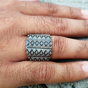 K&ouml;nnte beinhalten: Ein breiter Silberring mit geometrischem Muster. Der Ring ist aus Silber und hat eine strukturierte Oberfl&auml;che.