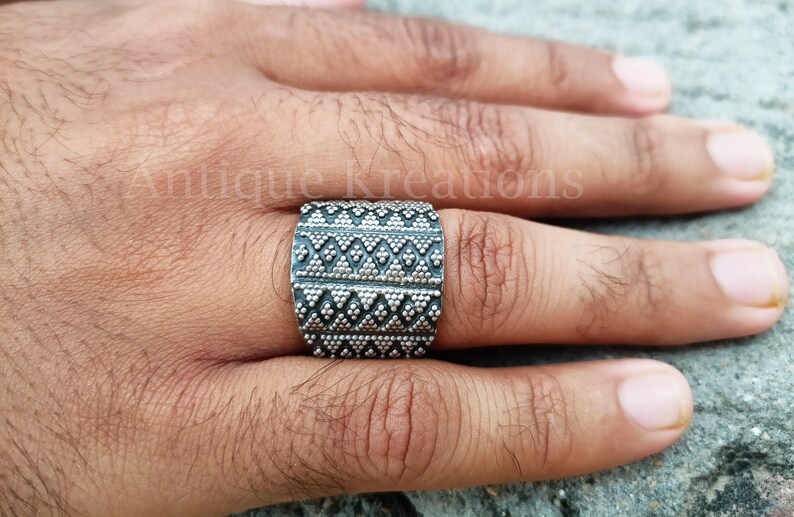 K&ouml;nnte beinhalten: Ein breiter Silberring mit geometrischem Muster. Der Ring ist aus Silber und hat eine strukturierte Oberfl&auml;che.