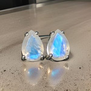 Può includere: Un paio di orecchini a goccia d'argento con pietre di luna iridescenti.