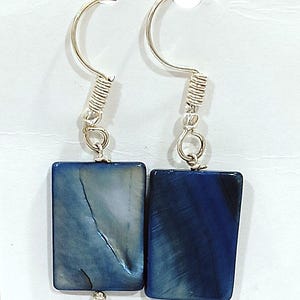 Puede incluir: Un par de pendientes de plata con colgantes rectangulares en forma de concha azul y blanca.