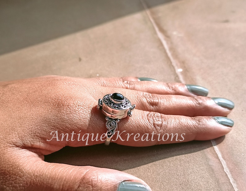 K&ouml;nnte beinhalten: Ein silberner Ring mit einem schwarzen Stein und filigranen Details. Der Ring ist &ouml;ffnungsf&auml;hig und hat ein kleines Fach im Inneren.
